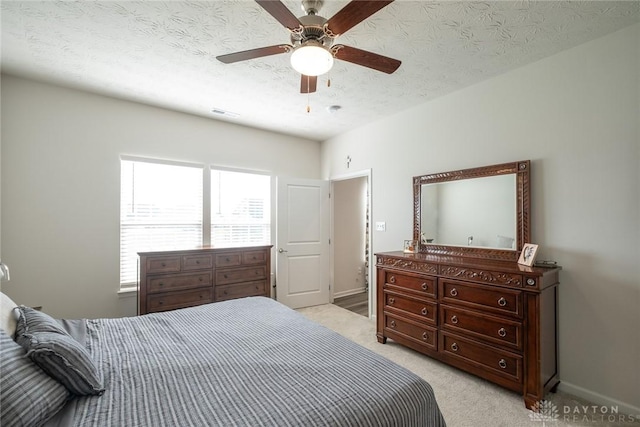bedroom with light colored carpet, ceiling fan, visible vents, and a textured ceiling