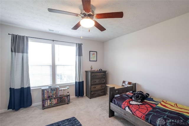 carpeted bedroom with a ceiling fan, visible vents, and a textured ceiling