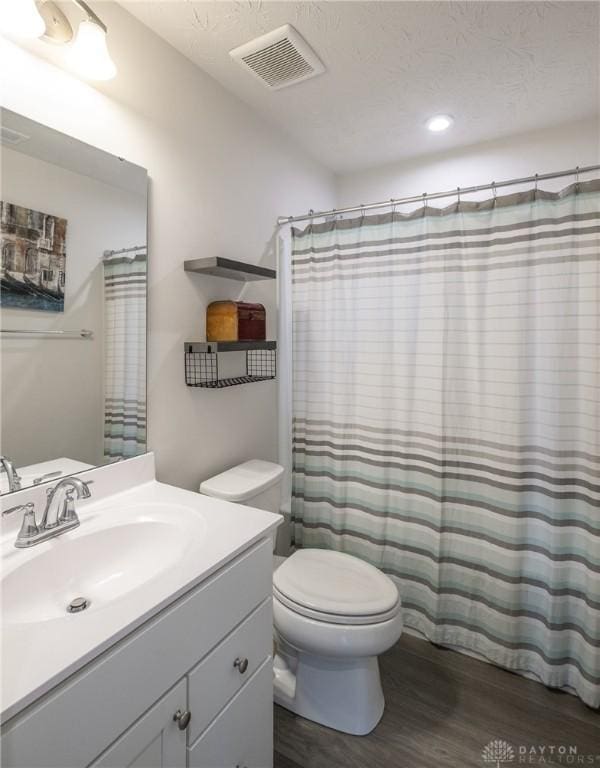 full bathroom with vanity, curtained shower, toilet, visible vents, and wood finished floors