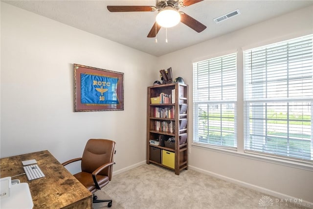home office featuring a ceiling fan, visible vents, light carpet, and baseboards