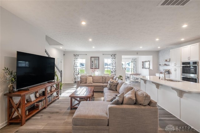 living area with stairway, visible vents, baseboards, recessed lighting, and wood finished floors