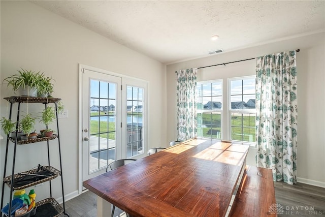 dining space with visible vents, wood finished floors, and baseboards