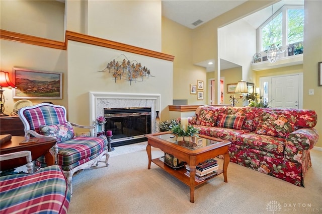 carpeted living area featuring visible vents, high vaulted ceiling, and a high end fireplace