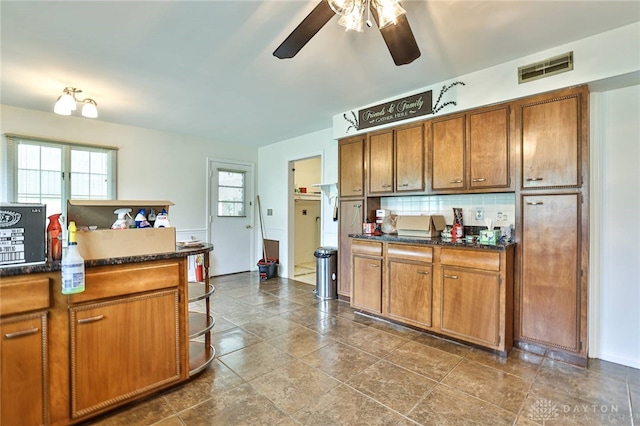 kitchen featuring backsplash, dark countertops, ceiling fan, and brown cabinetry
