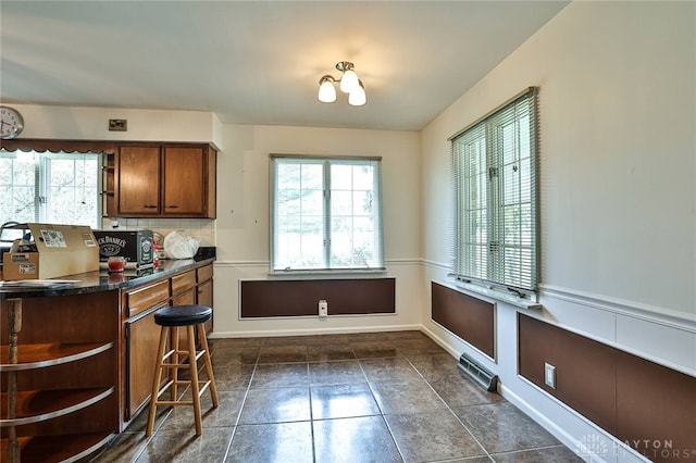 10699 Hamilton Ave, Cincinnati, OH 45231 - kitchen featuring dark countertops, open shelves, brown cabinetry, decorative backsplash, and a kitchen breakfast bar
