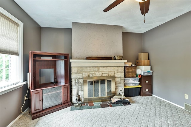 carpeted living area with a ceiling fan, baseboards, visible vents, and a fireplace