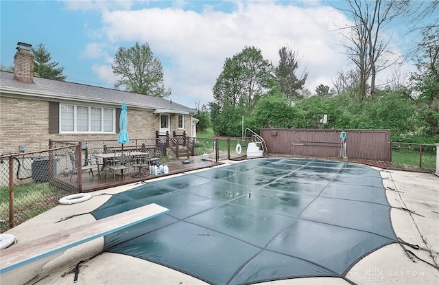 view of pool featuring a fenced in pool, a diving board, fence, and a wooden deck