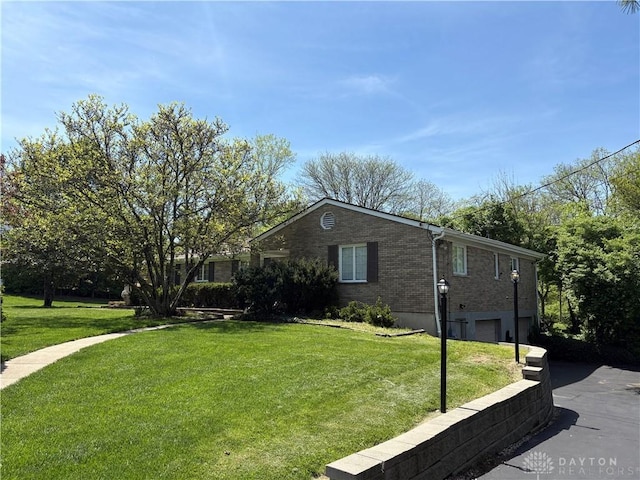 view of front of property featuring brick siding, driveway, a front lawn, and a garage