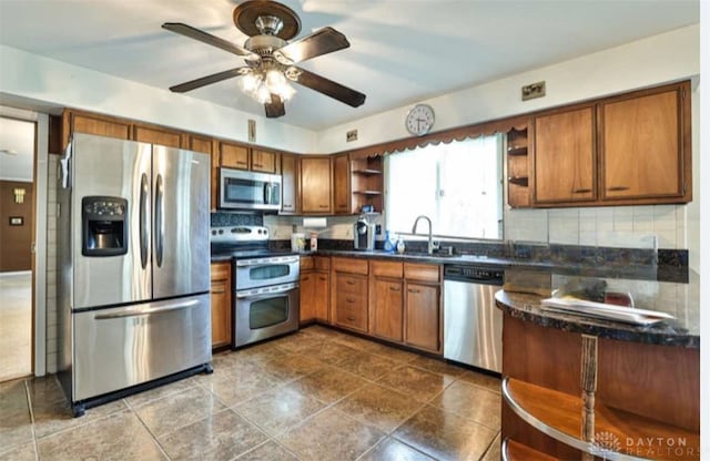 10699 Hamilton Ave, Cincinnati, OH 45231 - kitchen with appliances with stainless steel finishes, open shelves, dark countertops, a sink, and brown cabinets
