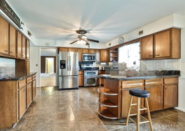10699 Hamilton Ave, Cincinnati, OH 45231 - kitchen featuring open shelves, stainless steel appliances, a peninsula, and brown cabinetry