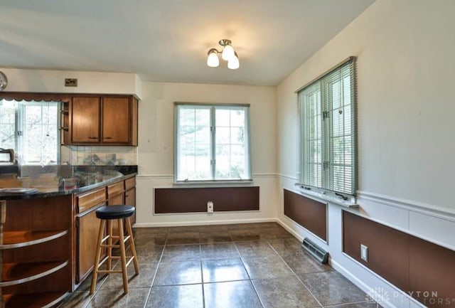 10699 Hamilton Ave, Cincinnati, OH 45231 - kitchen featuring healthy amount of natural light, brown cabinetry, dark countertops, and tasteful backsplash