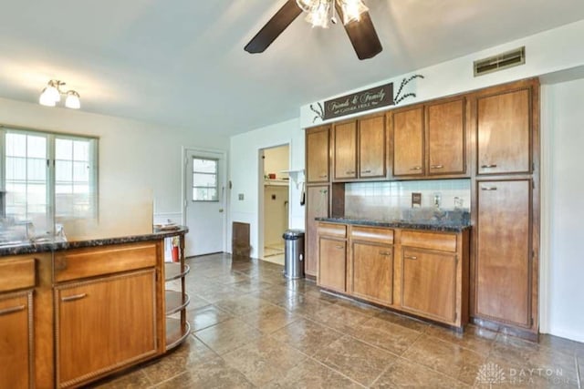 10699 Hamilton Ave, Cincinnati, OH 45231 - kitchen featuring a ceiling fan, brown cabinets, decorative backsplash, and dark stone counters