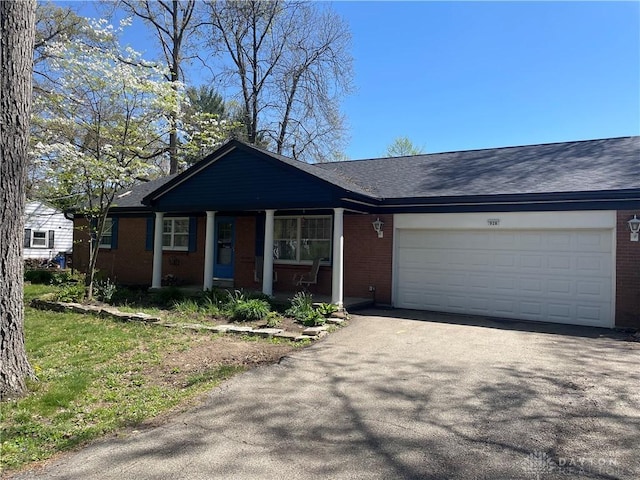 928 Shady Ln, Beavercreek, OH 45434 - ranch-style house with brick siding, driveway, a garage, a porch, and roof with shingles