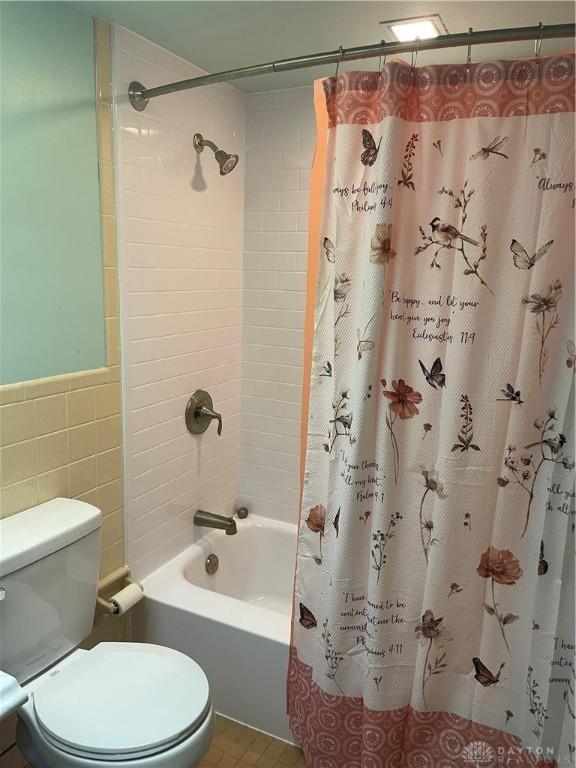 928 Shady Ln, Beavercreek, OH 45434 - bathroom featuring shower / bathtub combination with curtain, tile walls, toilet, wainscoting, and tile patterned flooring