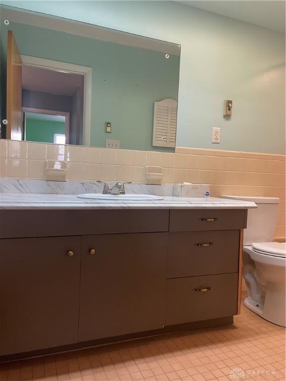 928 Shady Ln, Beavercreek, OH 45434 - bathroom featuring vanity, tile walls, toilet, a wainscoted wall, and tile patterned flooring