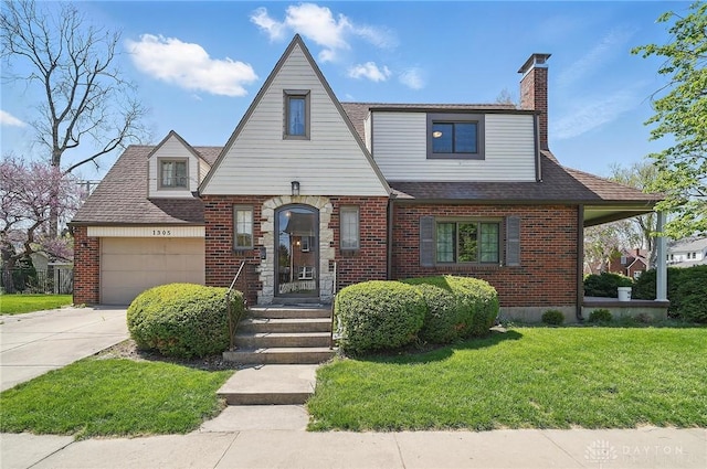 tudor home with a chimney, brick siding, driveway, a front yard, and an attached garage