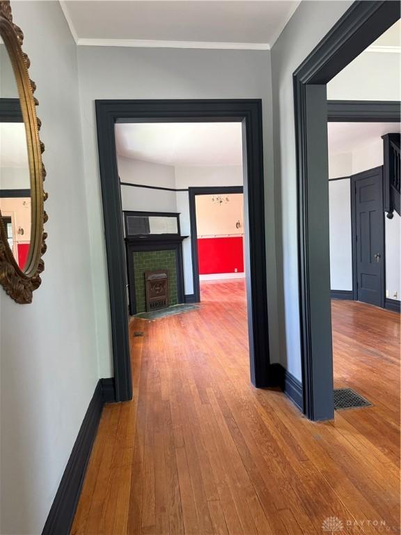 hall with visible vents, baseboards, crown molding, and wood-type flooring