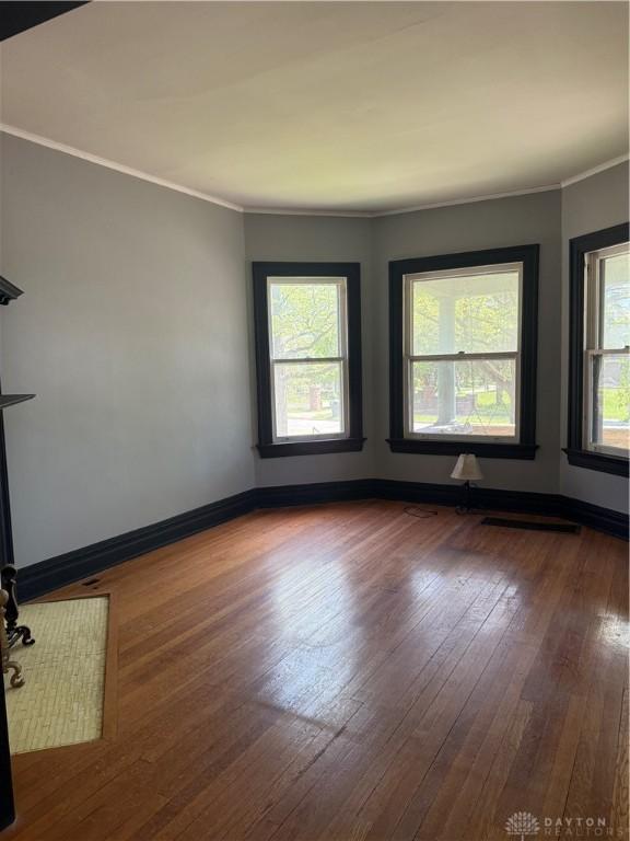 unfurnished room featuring ornamental molding, hardwood / wood-style floors, and baseboards
