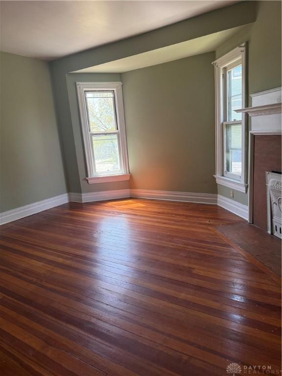 unfurnished living room with a fireplace with flush hearth, dark wood finished floors, and baseboards