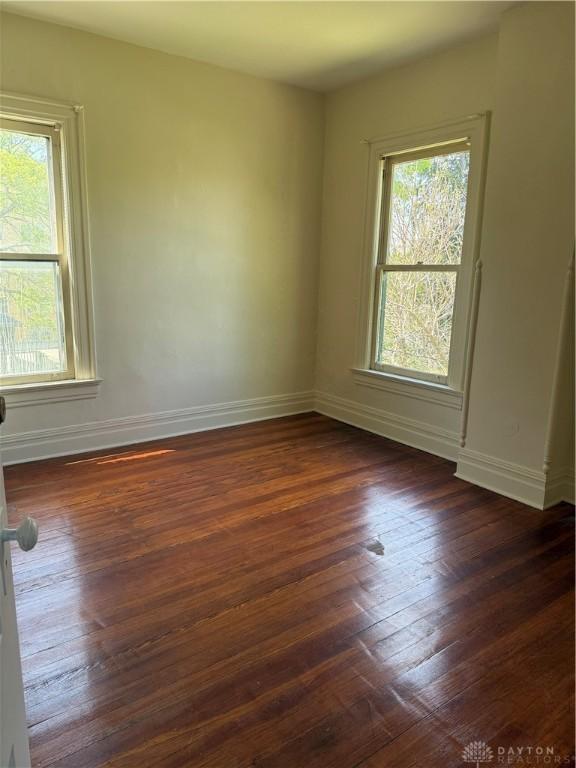 spare room with dark wood-style floors and baseboards