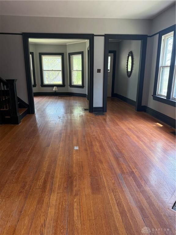 unfurnished living room with hardwood / wood-style floors, stairway, and baseboards