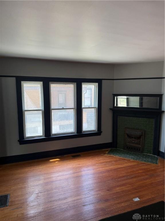 unfurnished living room with wood finished floors, visible vents, and baseboards