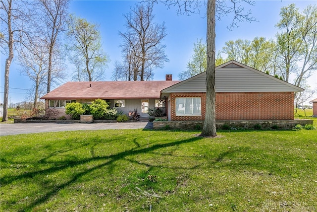 ranch-style house with brick siding, a chimney, and a front yard