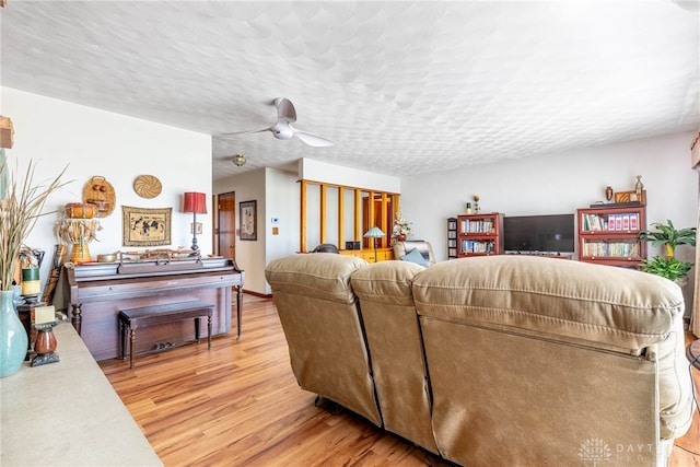 living area featuring a ceiling fan, light wood finished floors, and a textured ceiling