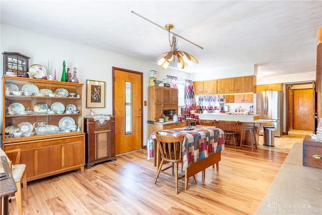 dining area with light wood-style floors and a chandelier