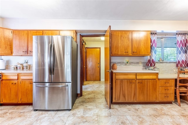 kitchen with light countertops, freestanding refrigerator, and brown cabinetry