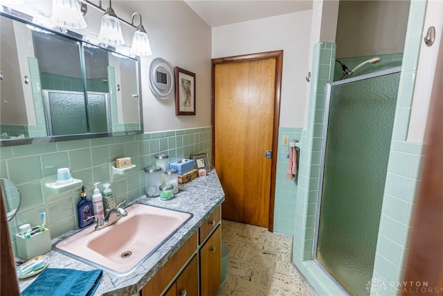 full bath featuring vanity, tile walls, a wainscoted wall, and a shower stall