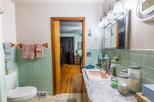 bathroom featuring visible vents, a wainscoted wall, toilet, and tile walls