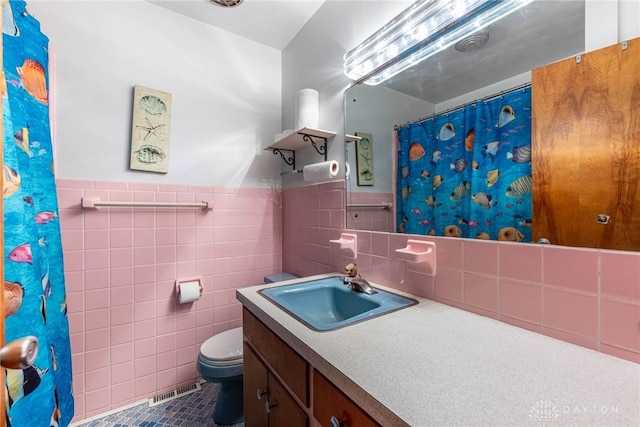 bathroom featuring visible vents, vanity, toilet, and tile walls