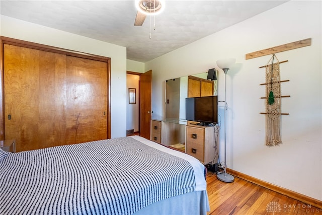 bedroom featuring baseboards, ceiling fan, light wood finished floors, and a closet