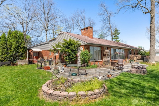 back of house featuring brick siding, a fire pit, a patio area, and a chimney