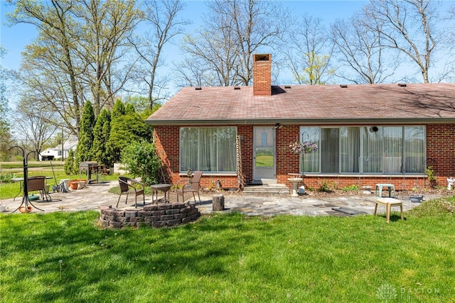 rear view of property featuring a yard, brick siding, a chimney, and a patio area
