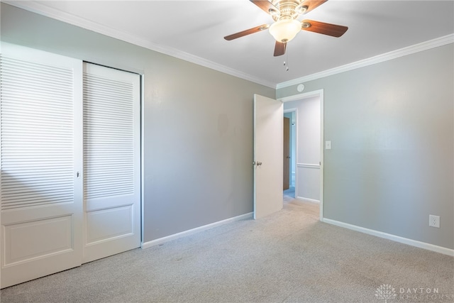 unfurnished bedroom featuring a ceiling fan, crown molding, baseboards, a closet, and carpet flooring