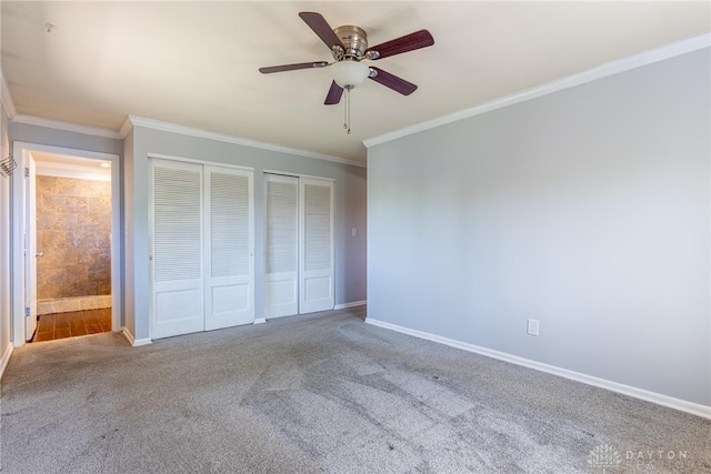 unfurnished bedroom with crown molding, ceiling fan, carpet, two closets, and baseboards