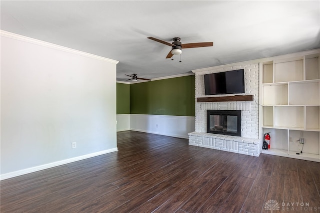 unfurnished living room with crown molding, a brick fireplace, a ceiling fan, baseboards, and wood finished floors