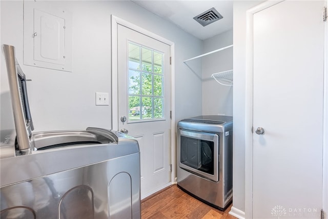 washroom with laundry area, washer and clothes dryer, light wood finished floors, and visible vents