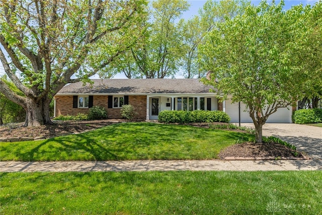 ranch-style home with an attached garage, a front yard, brick siding, and concrete driveway