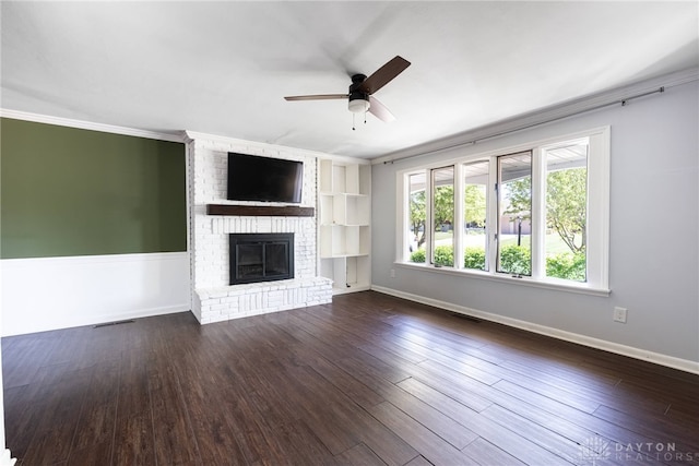 unfurnished living room with crown molding, a ceiling fan, dark wood-style flooring, and a fireplace