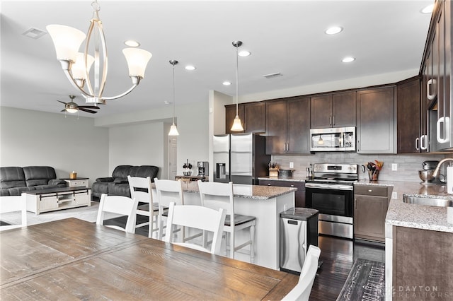 1621 Stonebury Ct, Xenia, OH 45385 - kitchen featuring stainless steel appliances, a sink, dark brown cabinets, a ceiling fan, and a center island