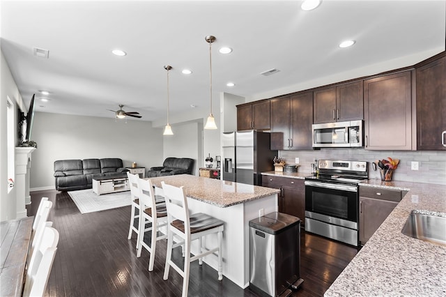 1621 Stonebury Ct, Xenia, OH 45385 - kitchen with appliances with stainless steel finishes, dark brown cabinets, a breakfast bar, light stone countertops, and open floor plan