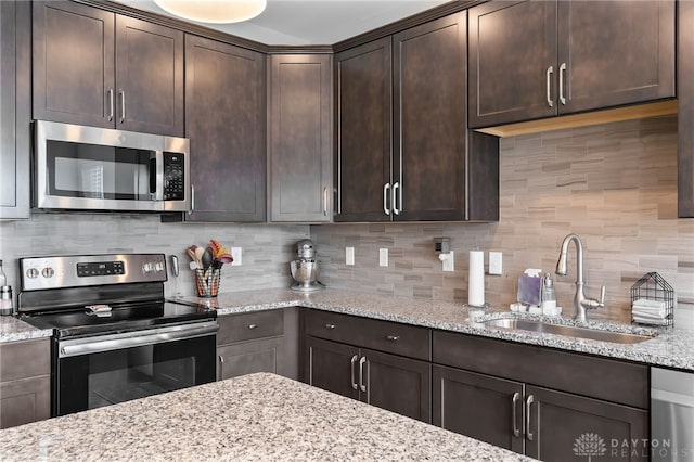 1621 Stonebury Ct, Xenia, OH 45385 - kitchen featuring appliances with stainless steel finishes, a sink, light stone counters, and dark brown cabinets