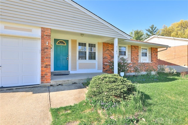 entrance to property with a porch, a yard, and brick siding