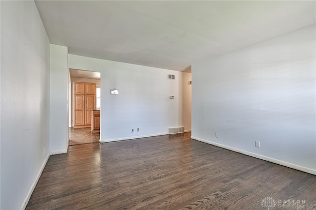 spare room with visible vents, dark wood finished floors, and baseboards