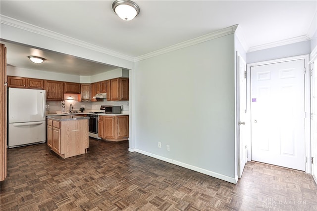 kitchen featuring a sink, a center island, freestanding refrigerator, baseboards, and ornamental molding