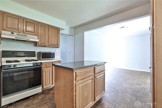 kitchen featuring dark countertops, gas range gas stove, a center island, stainless steel microwave, and under cabinet range hood