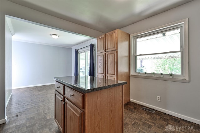 kitchen featuring baseboards, a center island, visible vents, and a healthy amount of sunlight